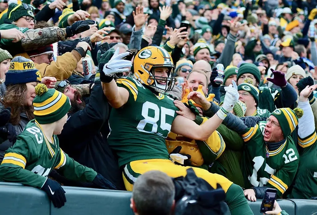 A Packers player leaping into the Lambeau Field stands